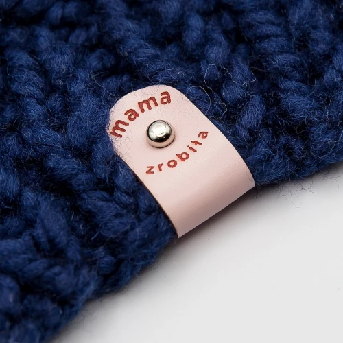 Metka „Mama zrobiła” w odcieniu jasnego różu na dziecięcym sweterku.