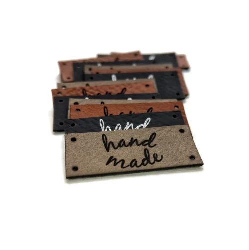 Zbliżenie na dwurzędowy układ napisu hand made na jasnoszarej naszywce o wymiarach 35x15 mm.webp